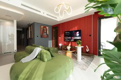 a living room with a green couch and red walls at Luxury 3BR Skyline Apartment - Sobha The Crest Dubai in Dubai