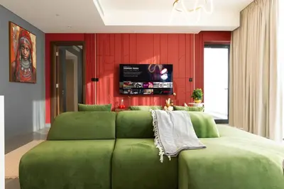 a green couch in a room with red walls at Luxury 3BR Skyline Apartment - Sobha The Crest Dubai in Dubai