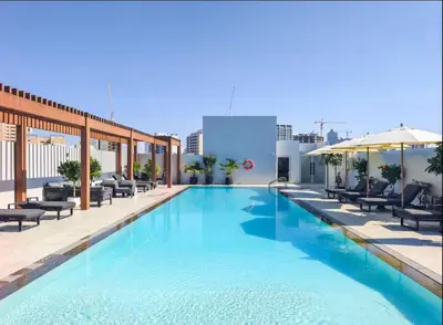 a large swimming pool with chairs and umbrellas on a building at Vogue JVC Luma22 near Circle Mall, Studio Apartment with Balcony and Vibrant Community View, Access to all Amenities in Dubai