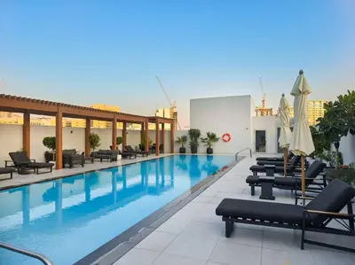 a large swimming pool with lounge chairs and umbrellas at Vogue JVC Luma22 near Circle Mall, Studio Apartment with Balcony and Vibrant Community View, Access to all Amenities in Dubai