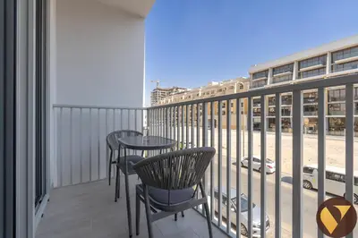 a balcony with two tables and chairs and a street at Vogue JVC Luma22 near Circle Mall, Studio Apartment with Balcony and Vibrant Community View, Access to all Amenities in Dubai