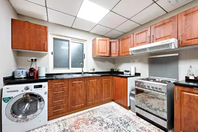 a kitchen with wooden cabinets and a washer at VayK - Welcoming and Warm 2BR in JLT in Dubai