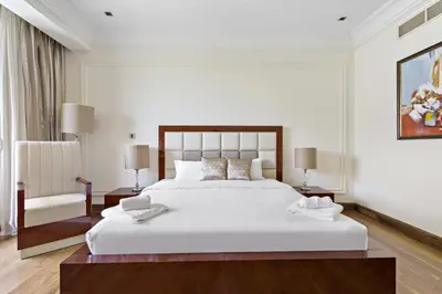 a bedroom with a large white bed and a chair at VayK - Stylish 1BR in Palm Jumeirah with Secluded Beach Access in Dubai