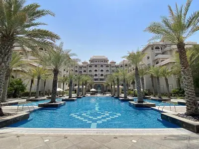 a large swimming pool with palm trees in front of a building at VayK - Stylish 1BR in Palm Jumeirah with Secluded Beach Access in Dubai