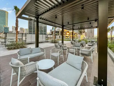 a patio with chairs and tables on a roof at Elevated 2 Bedroom with Khalifa view in Peninsula in Dubai