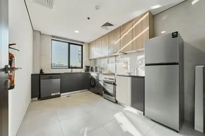 a kitchen with stainless steel appliances and a large window at Chic 1BR Getaway in Tulip Oasis 9 Majan in Dubai
