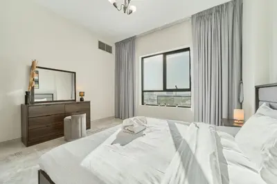 a white bedroom with a large bed and a large window at Chic 1BR Getaway in Tulip Oasis 9 Majan in Dubai