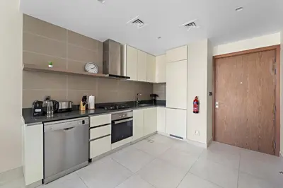 a kitchen with white cabinets and a wooden door at VayK - Chic Marina-Front 1BR in a Luxurious Location in Dubai