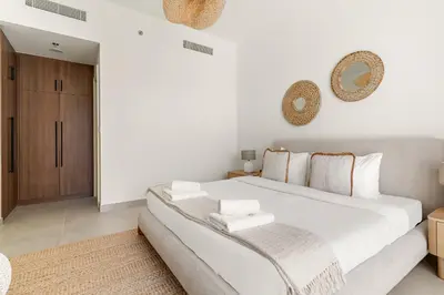 a white bedroom with a large white bed with pillows at VayK - Chic 2BR in Town Square with Pool View in Dubai