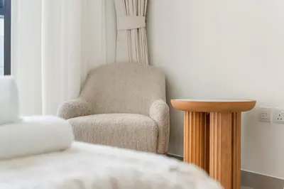 a bedroom with a chair and a side table at VayK - Chic 2BR in Town Square with Pool View in Dubai