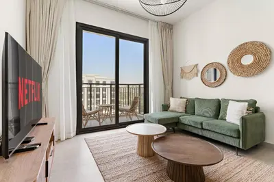 a living room with a green couch and a tv at VayK - Chic 2BR in Town Square with Pool View in Dubai