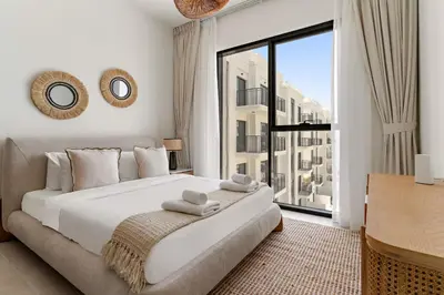 a bedroom with a large bed and a large window at VayK - Chic 2BR in Town Square with Pool View in Dubai