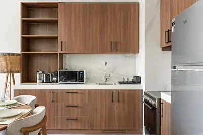 a kitchen with wooden cabinets and a table at VayK - Chic 2BR in Town Square with Pool View in Dubai