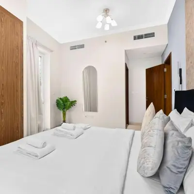 a bedroom with a white bed with two pillows at Heart of Downtown Luxury 1BHK Dunya in Dubai
