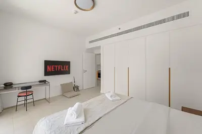 a white bedroom with a bed and a desk at VayK - Feel the Festive Vibe in Cozy 1BR with Beach Access in Dubai