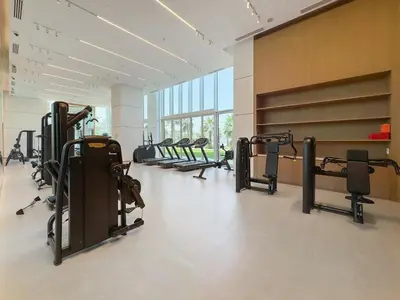 a gym with several rows of treadmills and machines at VayK - Feel the Festive Vibe in Cozy 1BR with Beach Access in Dubai