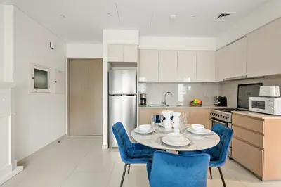 a kitchen with a table and blue chairs in a kitchen at VayK - Iconic 1BR in Downtown in Dubai