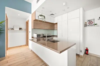 a kitchen with white cabinets and a counter top at VayK - Bright and Stylish 1BR in Marina in Dubai