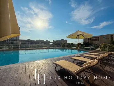 a swimming pool with lounge chairs and an umbrella at LUX The Palm Sea View Studio in Dubai