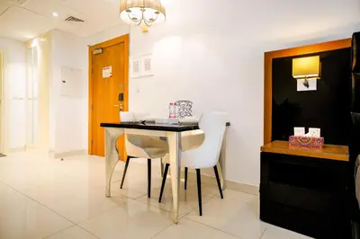 a dining room with a table and white chairs at Escape24 Cozy Studio at Capital Bay near Burj Khalifa in Dubai