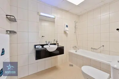 a bathroom with a sink and a tub and a toilet at Luxury Spacious 1BR JVC 2Bath Pool Gym in Dubai