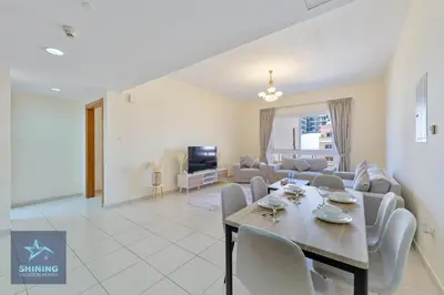 a dining room and living room with a table and chairs at Luxury Spacious 1BR JVC 2Bath Pool Gym in Dubai