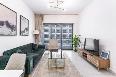 a living room with a green couch and a tv at HAVN- 1 Bedroom in Binghatti, Al Jaddaf in Dubai