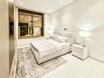a white bedroom with a bed and a window at Luxury Studio Apartment Near Jumeirah Beach in Dubai