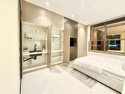 a white bedroom with a bed and a sink at Luxury Studio Apartment Near Jumeirah Beach in Dubai