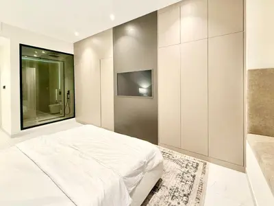 a bedroom with a white bed and a tv at Luxury Studio Apartment Near Jumeirah Beach in Dubai