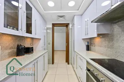 a kitchen with white cabinets and a hallway at Skyline Bliss Luxury Apartment Dubai in Dubai