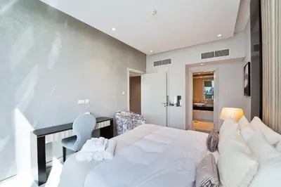 a bedroom with a large white bed and a chair at Refined 1 bedroom - Upper Crest - Near Dubai Mall in Dubai