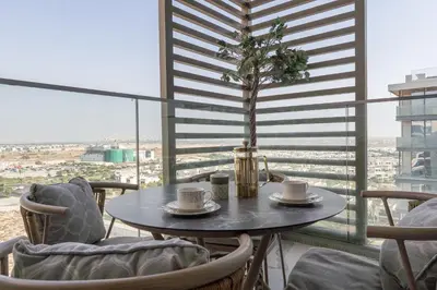 a table with two cups and a tree on a balcony at Vogue Dubai Hills The Pinnacle near Dubai Hills Mall and Park, One Bedroom Apartment with Large Balcony and City View, Access to all Amenities in Dubai