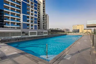 a large blue swimming pool in front of a building at Vogue Dubai Hills The Pinnacle near Dubai Hills Mall and Park, One Bedroom Apartment with Large Balcony and City View, Access to all Amenities in Dubai