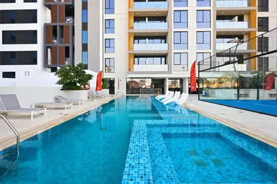 a swimming pool with chairs and a building at Aura by Grovy Studio - Parking, Sauna&Gym, Pool - by Rentujemy in Dubai