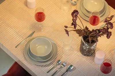 a table with plates and glasses and a vase with flowers at Stylish Studio Loft with Outdoor Patio in JVC in Dubai