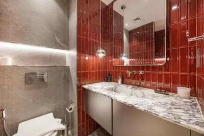 a red tiled bathroom with a sink and a toilet at Stylish Studio Loft with Outdoor Patio in JVC in Dubai