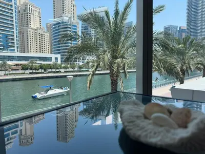 a glass table with a boat in the water in a city at Modern 2 Bedroom Apartment in Dubai Marina in Dubai