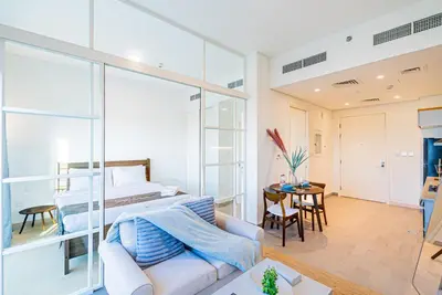 a bedroom with a bed and a living room with a couch at Escape24 Contemporary 1BR with City Views in Dubai Hills in Dubai