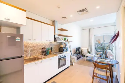 a kitchen with white cabinets and a table at Escape24 Contemporary 1BR with City Views in Dubai Hills in Dubai