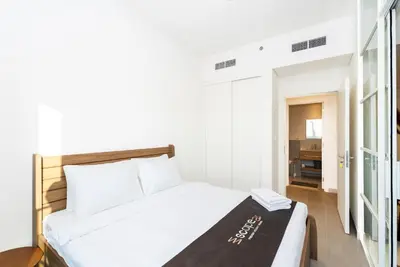 a bedroom with a white bed and a bathroom at Escape24 Contemporary 1BR with City Views in Dubai Hills in Dubai