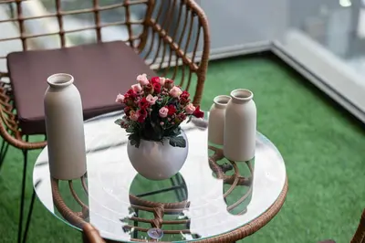 a glass table with a vase with flowers on it at Brand New Building! 2 Double Bed! Ideal Location with 5-star Pool and Gym! in Dubai