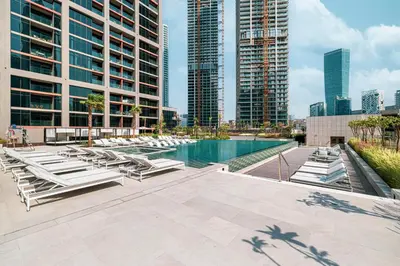 a pool with chaise lounge chairs and buildings at Brand New Building! 2 Double Bed! Ideal Location with 5-star Pool and Gym! in Dubai