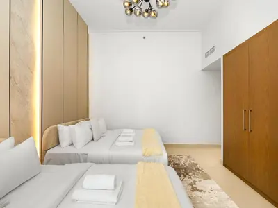 a white bedroom with two beds and a cabinet at Stunning 4BR Burj View Pool &Gym in Dubai