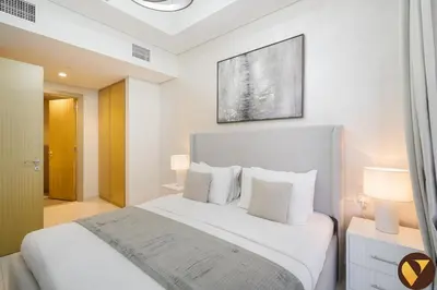 a white bedroom with a bed and two lamps at Vogue Business Bay Aykon City Close to Downtown Burj Khalifa and Dubai Mall Burj Khalifa and Dubai Mall, One Bedroom Apartment with Balcony and City View, Access to all Amenities in Dubai