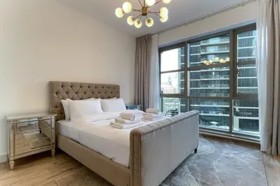 a bedroom with a large bed and a large window at Elite LUX Holiday Homes - Cozy City Escape in Standpoint Downtown in Dubai