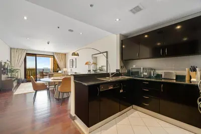 a kitchen with black cabinets and a dining room at Palm Retreat - Anantara North - Palm Jumeirah in Dubai