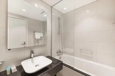a white bathroom with a sink and a shower at High Floor Balcony Suite 8 mins to Burj Khalifa in Dubai