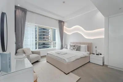 a white bedroom with a large bed and a chair at Gala Guests - Marina Views Bright Balcony Collection in Dubai