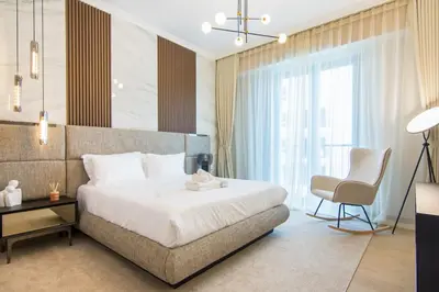 a bedroom with a bed and a chair and a window at Cozy 3BR Sea-View Apartment in La Rive 1 in Dubai